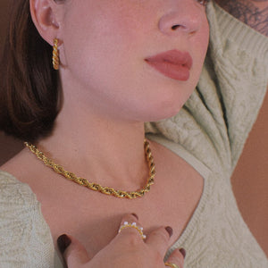 Gold rope chain necklace and gold rope hoop earrings on girl with rose arm tattoo
